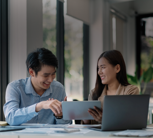Two HR professionals at a desk in a modern office, reviewing information on the MOVEPLUS relocation platform