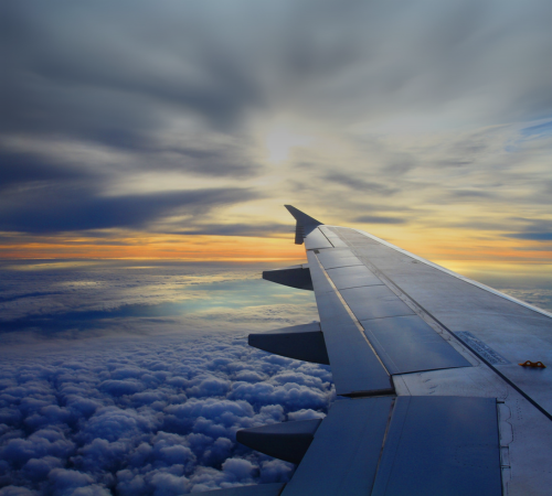 An image of a plane wing with a sunset in the background